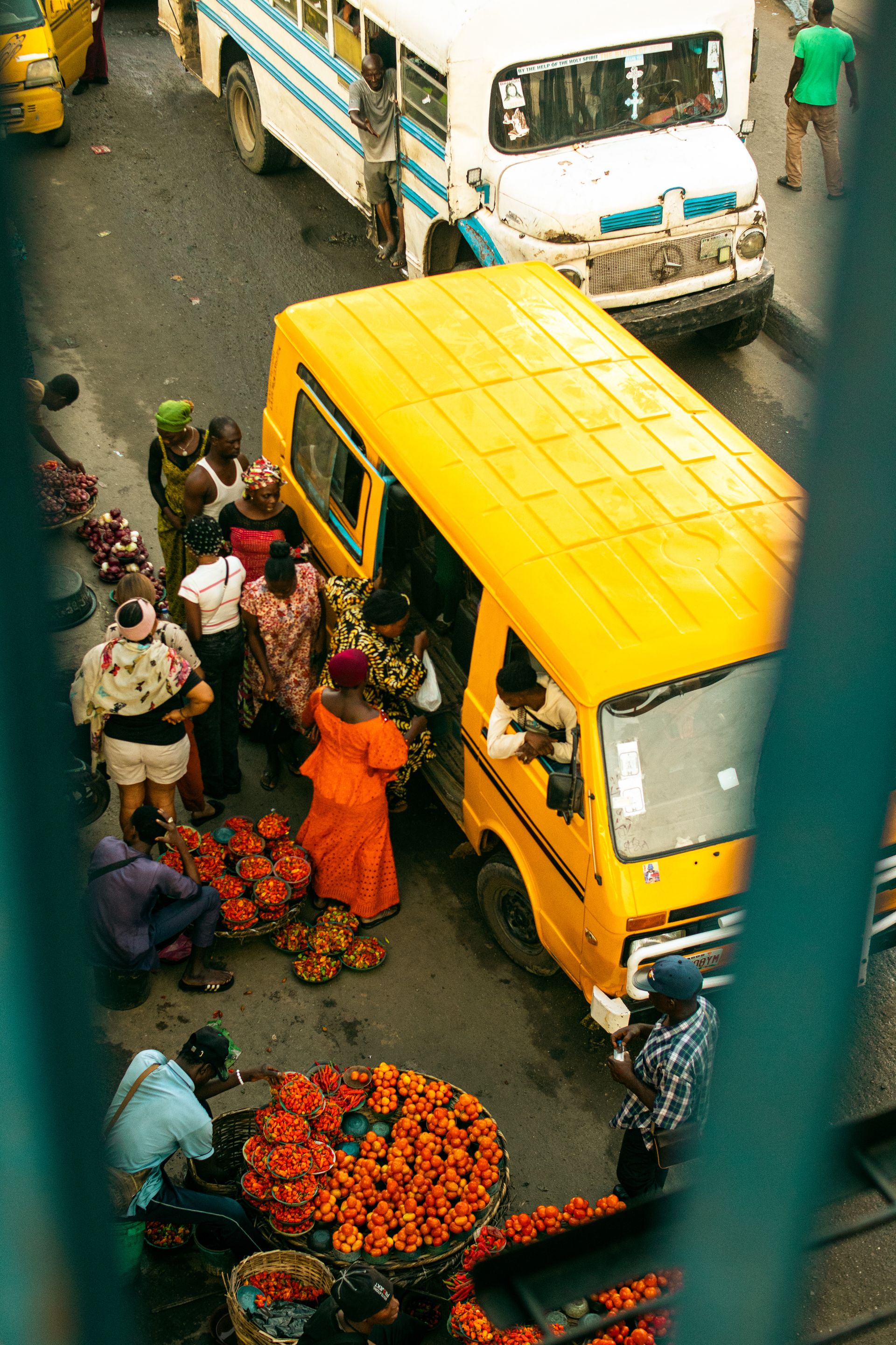 Merchants, produce and a yellow bus at a busy market in Lagos